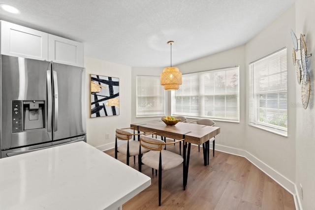 dining area with light hardwood / wood-style floors and a textured ceiling