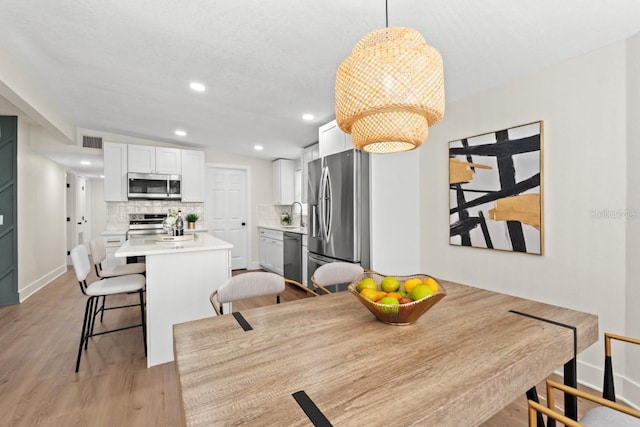 dining area with sink, vaulted ceiling, and light wood-type flooring