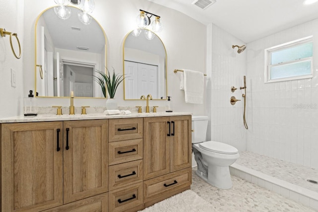 bathroom featuring tiled shower, vanity, and toilet