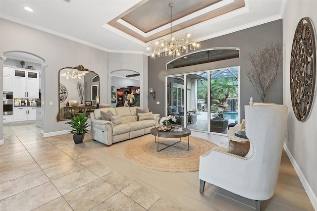 tiled living room with a tray ceiling, ornate columns, crown molding, and a chandelier