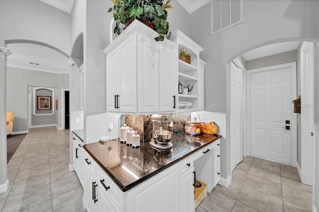 kitchen featuring decorative columns, dark stone countertops, white cabinetry, and light tile patterned floors