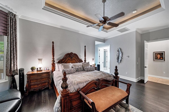 bedroom featuring a raised ceiling, ceiling fan, a textured ceiling, and ornamental molding