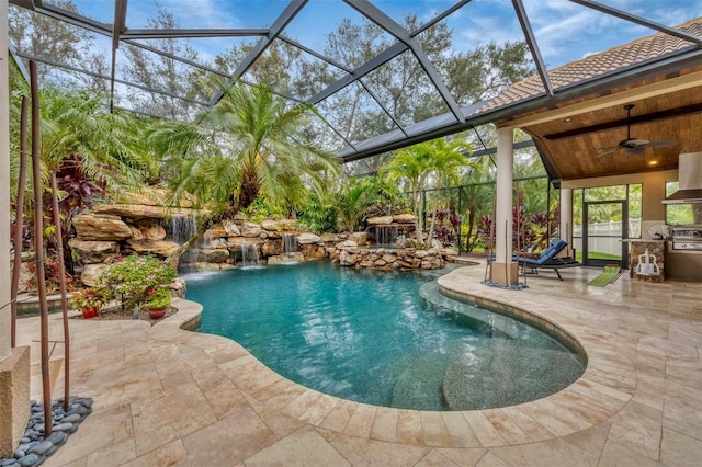 view of pool featuring an outdoor kitchen, pool water feature, ceiling fan, grilling area, and a patio