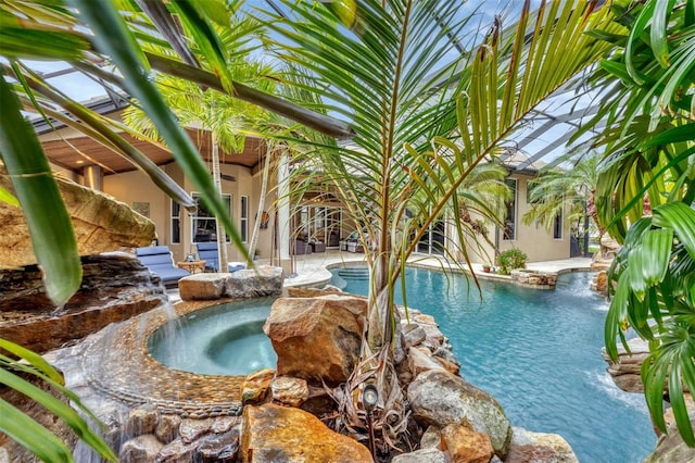 view of swimming pool featuring glass enclosure and an in ground hot tub