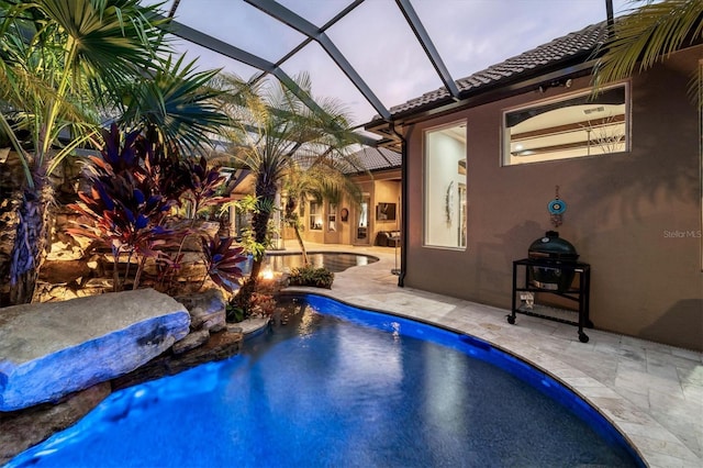 pool at dusk featuring a lanai and a patio area