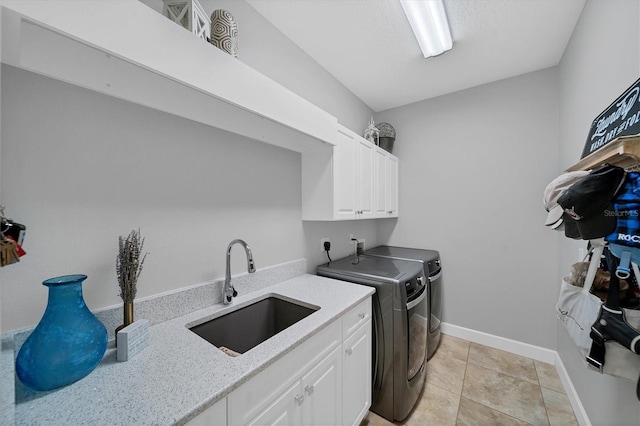 washroom featuring cabinet space, light tile patterned floors, baseboards, washing machine and dryer, and a sink