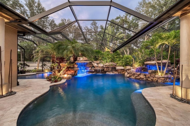 pool with a lanai, a patio area, a jacuzzi, and fence