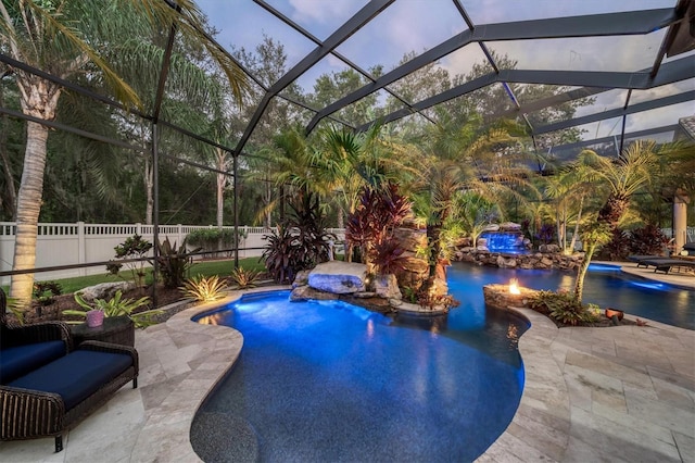 pool at dusk with a patio area, a lanai, a fenced in pool, and fence