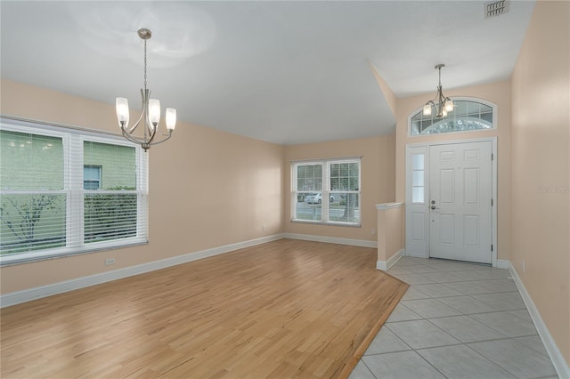 tiled foyer entrance featuring an inviting chandelier