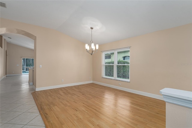 tiled spare room with a chandelier and lofted ceiling