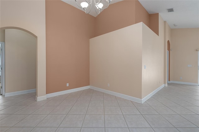 empty room featuring a chandelier, light tile patterned floors, and vaulted ceiling