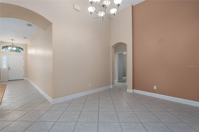 tiled spare room with a chandelier