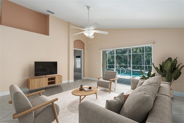 tiled living room featuring a textured ceiling, ceiling fan, and lofted ceiling