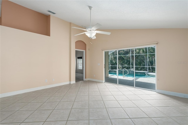 tiled spare room featuring a textured ceiling, ceiling fan, and lofted ceiling