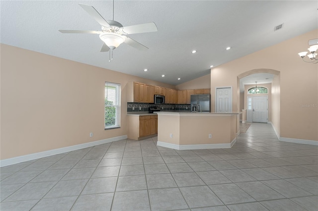 kitchen featuring appliances with stainless steel finishes, a center island, light tile patterned floors, and lofted ceiling