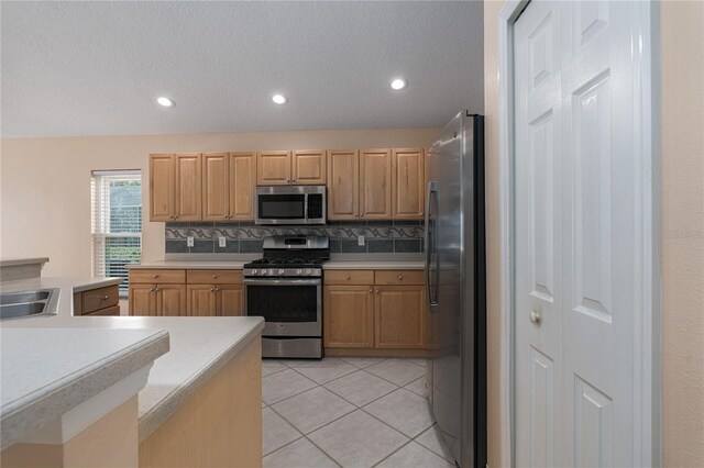 kitchen with sink, stainless steel appliances, decorative backsplash, light brown cabinetry, and light tile patterned flooring