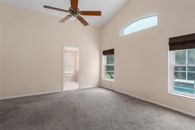 carpeted empty room featuring ceiling fan, high vaulted ceiling, and a healthy amount of sunlight