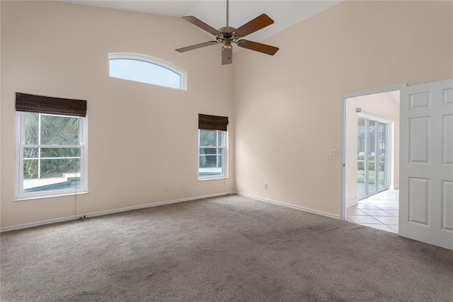 carpeted spare room with ceiling fan and high vaulted ceiling