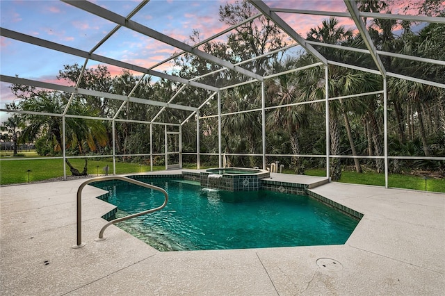 pool at dusk featuring glass enclosure, a patio area, and an in ground hot tub