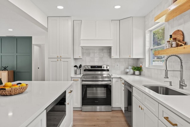 kitchen featuring premium range hood, appliances with stainless steel finishes, sink, and white cabinets