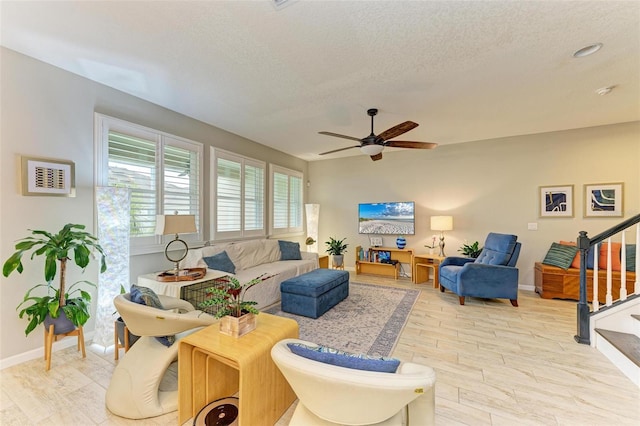 living room with ceiling fan, a textured ceiling, and light hardwood / wood-style flooring