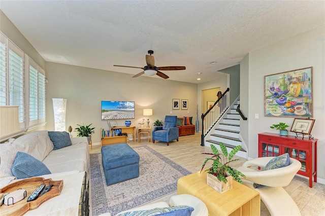 living room with ceiling fan, a textured ceiling, and light wood-type flooring