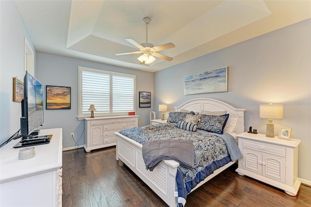 bedroom with a raised ceiling, ceiling fan, and dark hardwood / wood-style flooring