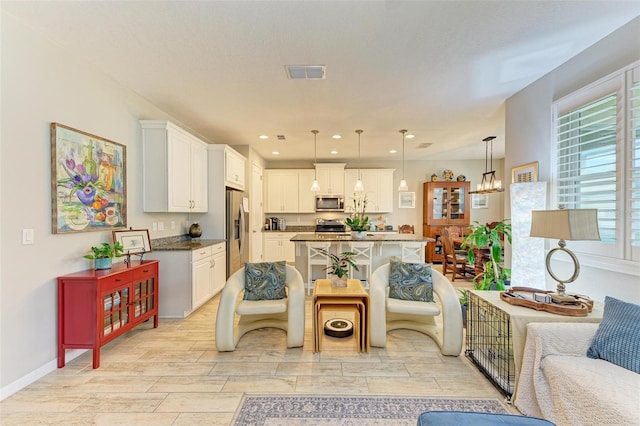 kitchen featuring a breakfast bar, white cabinets, hanging light fixtures, stainless steel appliances, and an inviting chandelier