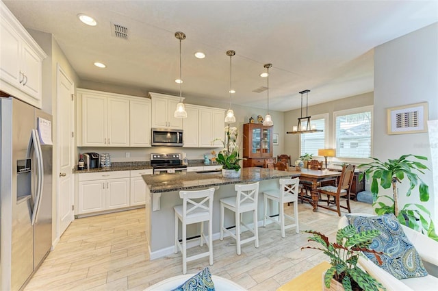 kitchen featuring a kitchen island with sink, stainless steel appliances, and white cabinets