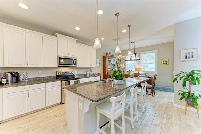 kitchen featuring white cabinetry, appliances with stainless steel finishes, sink, and a center island with sink