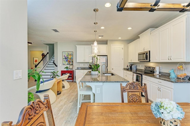 kitchen featuring white cabinetry, sink, stainless steel appliances, and dark stone counters