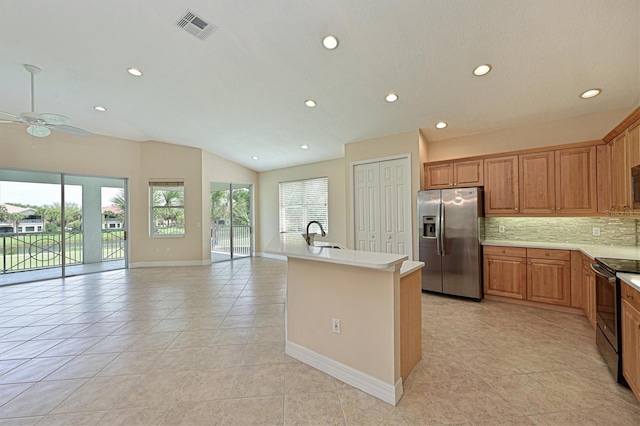 kitchen featuring black electric range oven, backsplash, ceiling fan, stainless steel fridge, and an island with sink