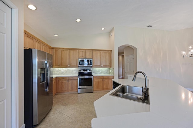 kitchen featuring appliances with stainless steel finishes, tasteful backsplash, sink, light tile patterned floors, and lofted ceiling