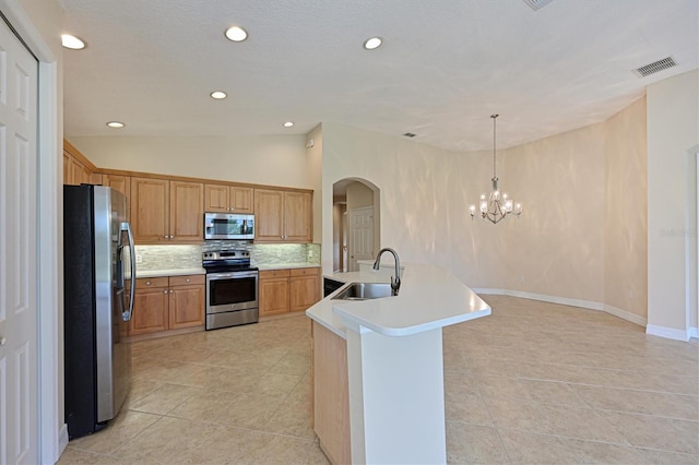 kitchen with backsplash, stainless steel appliances, sink, a center island with sink, and hanging light fixtures