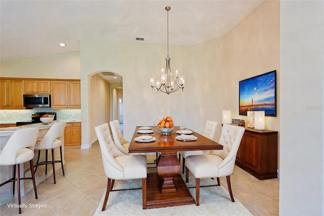 tiled dining space featuring lofted ceiling and a notable chandelier