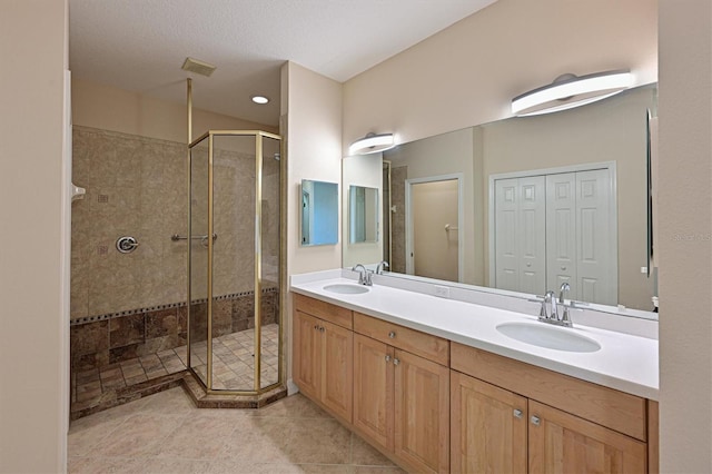 bathroom featuring tile patterned flooring, a textured ceiling, vanity, and a shower with door