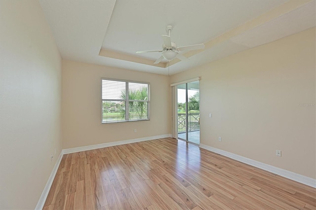 spare room with ceiling fan, a raised ceiling, and light hardwood / wood-style flooring