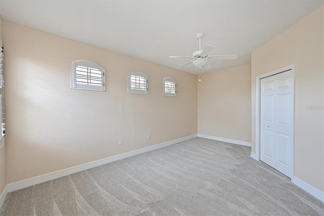 empty room with ceiling fan and light carpet