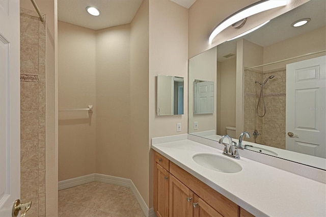 bathroom featuring tile patterned flooring, a tile shower, and vanity