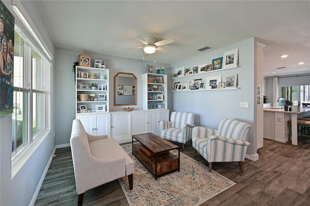 sitting room with ceiling fan, dark hardwood / wood-style flooring, and built in shelves