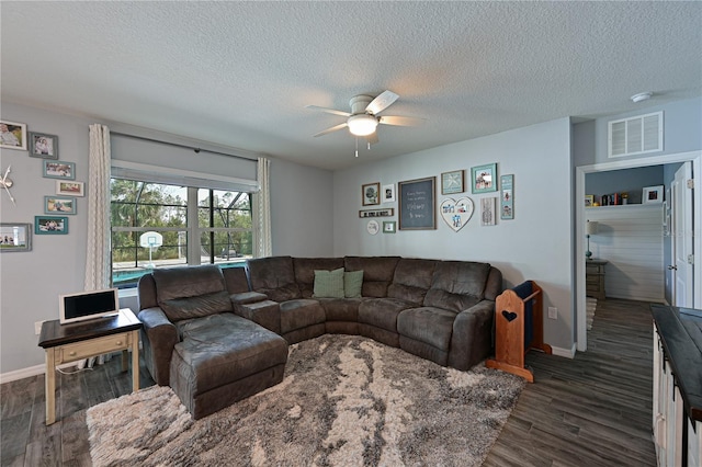 living room featuring dark hardwood / wood-style floors, ceiling fan, and a textured ceiling