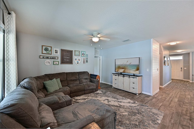 living room featuring ceiling fan, wood-type flooring, and a textured ceiling