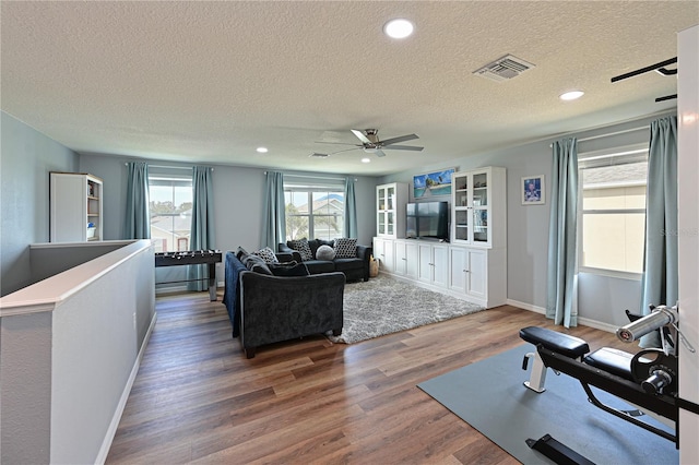 living room with ceiling fan, a textured ceiling, and hardwood / wood-style flooring