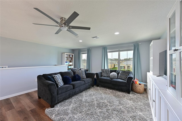 living room featuring ceiling fan, a textured ceiling, and dark wood-type flooring