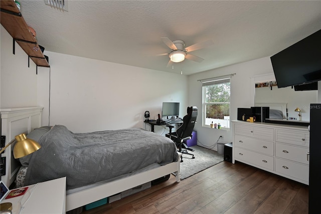 bedroom with ceiling fan, dark hardwood / wood-style flooring, and a textured ceiling