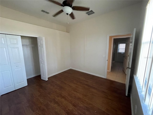 unfurnished bedroom with ceiling fan, a closet, and dark hardwood / wood-style floors