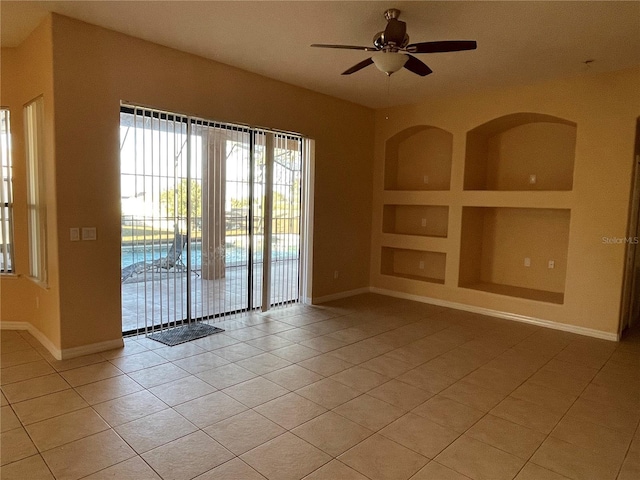 tiled empty room featuring ceiling fan and built in features