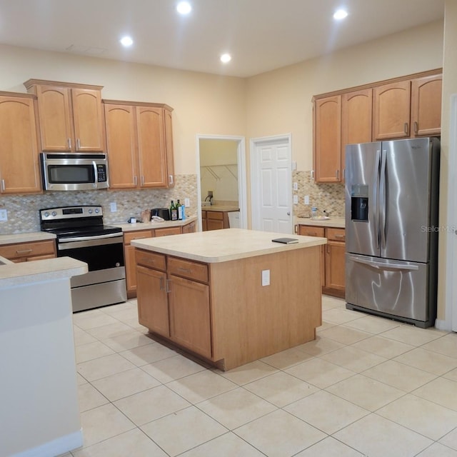 kitchen with appliances with stainless steel finishes, a center island, backsplash, and light tile patterned floors