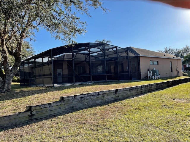 back of property featuring glass enclosure and a yard