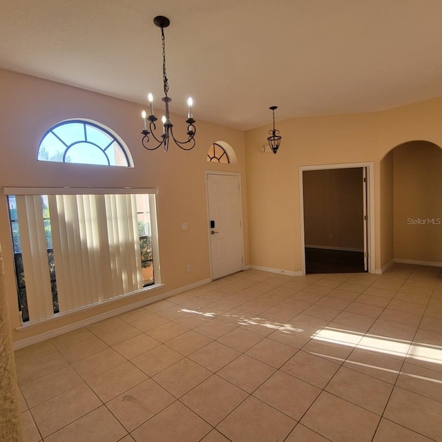 tiled empty room featuring an inviting chandelier